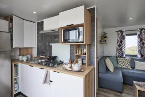 a kitchen and living room in a caravan at Camping Le Coin Charmant in Chauzon