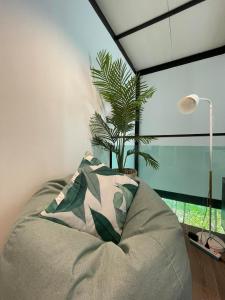 a couch with a pillow and a plant in a room at Peaceful & Contemporary Duplex Escape in Ban Thap Nang