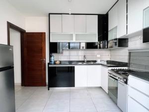 a kitchen with white cabinets and a black refrigerator at Modern 3BR Apt next to Hotel Dieu in Beirut
