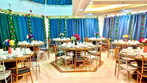 a dining room with tables and chairs and blue curtains at Penang Dream Banglo Sleeps 65 in Tanjung Bungah +46 photos