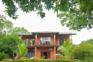 Cette maison en briques rouges dispose d'un balcon et d'arbres. dans l'établissement Sigiriya Cottage, à Sigirîya