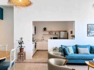 uma sala de estar com um sofá azul e uma cozinha em Bright Loft 4BR MarMikhael em Beirute