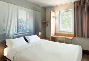 een slaapkamer met een groot wit bed en een raam bij B&B HOTEL Paris Nord Villepinte in Villepinte