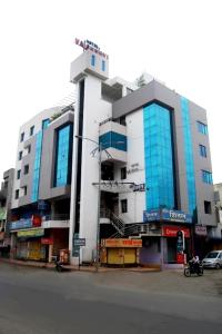 a large building with blue windows on a city street at Hotel Vaishnavi in Solapur