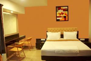 a bedroom with a bed and a television and chairs at Hotel Vaishnavi in Solapur