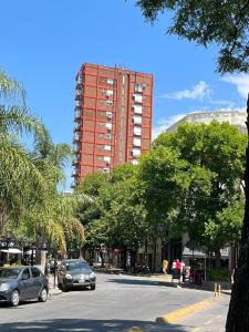 un edificio alto rojo con coches aparcados en una calle en Excelente monoambiente en Buenos Aires