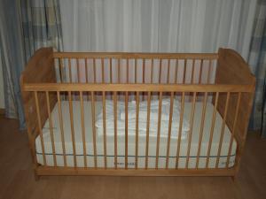 a wooden crib with white sheets in a room at Ferienwohnung Mengelberg in Markkleeberg