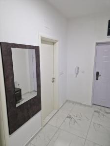 Habitación blanca con espejo en la pared en Lux Apartman, en Strumica