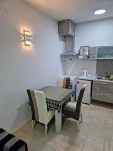 comedor con mesa y sillas y cocina en Lux Apartman, en Strumica