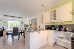 a kitchen with white cabinets and a dining table at Le monde de Lucy in Annoeullin +5 photos