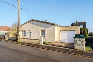 a white house with a garage on a street at Le monde de Lucy in Annoeullin