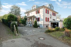 ein großes weißes Haus mit roten Fenstern und einer Auffahrt in der Unterkunft Ferienwohnung Schwarzwaldperle in Baden-Baden