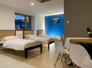 a room with four beds and a table and chairs at Tanie Noclegi Gliwice - Apartamenty Łowicka 28 in Gliwice +6 photos