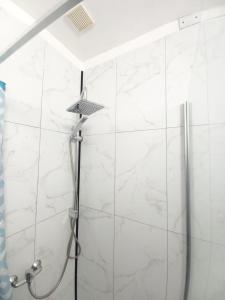 y baño con ducha y paredes de mármol blanco. en 2N Appartement en Eupen