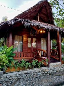 a small wooden house with a thatch roof at Tropical Jungle Hut in Bukit Lawang