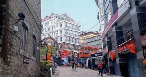 un gruppo di persone che camminano per una strada di città con edifici di HOTEL CLIFFTON ROYALS a Darjeeling