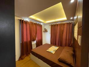 a small bedroom with a bed and red curtains at Cozy 2-bedroom Condo at Marcos Highway in Manila