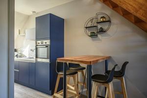 une cuisine avec des placards bleus, une table en bois et des tabourets dans l'établissement Le Duplex, proche centre-ville, à Quimper
