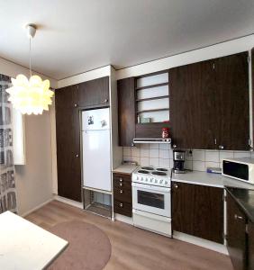 a kitchen with wooden cabinets and a white refrigerator at Spacious Northern City Apartment in Rovaniemi