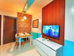 a living room with a table and a tv on a wall at Palawan Paradise Condotel 1L in Puerto Princesa City