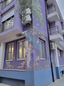 un murale sul lato di un edificio viola di Бутик хотел ресторант брасери Сажитариус a Kjustendil