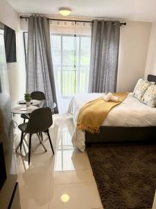 Un dormitorio con una cama y una mesa y una ventana. en Flat in umhlanga, en Durban