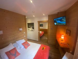 1 dormitorio con 1 cama y TV en la pared en Hôtel du Grand-Mont en Beaufort