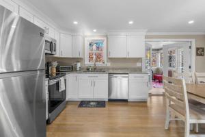 a kitchen with white cabinets and a stainless steel refrigerator at Cozy Spacious Home Walk to the Beach and 1 Mile to Downtown Hyannis in Barnstable