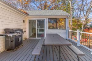 a picnic table on a deck with a grill at Cozy Spacious Home Walk to the Beach and 1 Mile to Downtown Hyannis in Barnstable