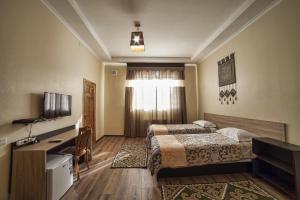 ein Hotelzimmer mit 2 Betten und einem Schreibtisch in der Unterkunft Ethno boutique Hotel Osh in Osch