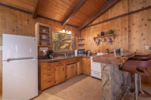 a kitchen with a white refrigerator and wooden walls at Donut Chalet with spa, BBQ grill, and firepit in Big Bear Lake