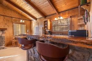 a bar with leather chairs in a room with wooden walls at Donut Chalet with spa, BBQ grill, and firepit in Big Bear Lake