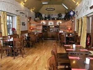 a restaurant with wooden floors and tables and chairs at The Ken Bridge Hotel in New Galloway