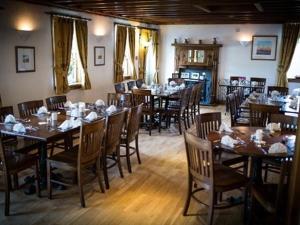 uma sala de jantar com mesas e cadeiras de madeira em The Ken Bridge Hotel em New Galloway