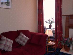 a living room with a red couch and a lamp at The Ken Bridge Hotel in New Galloway