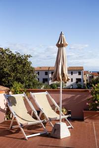 2 Liegestühle und ein Sonnenschirm auf einer Terrasse in der Unterkunft Agave Marina in Marciana Marina