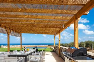a wooden pergola with a table and a grill at Villa Red Sunset by Estia in Sfakaki