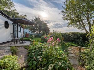 a garden with pink flowers and an umbrella at 1 Bed in Braunton 86987 in Braunton