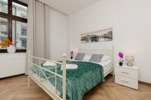 a white bedroom with a bed with a green blanket at Beautiful Studios Piotrkowska by Renters in Łódź