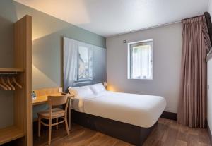 シャルトルにあるB&B HOTEL CHARTRES Le Coudrayのベッドとデスクが備わるホテルルームです。
