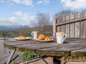 a wooden table with two plates of croissants and coffee cups at 2 bed property in Bala 86963 in Llandderfel