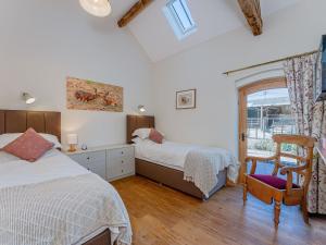 a bedroom with two beds and a chair and a window at 4 Bed in Church Stretton 87695 in Cardington