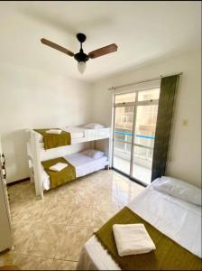 - une chambre avec 2 lits et un ventilateur de plafond dans l'établissement Apartamento encantador a uma quadra do melhor trecho da Praia do forte- Cabo Frio, à Cabo Frio