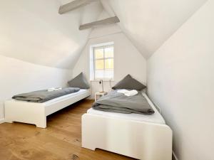 2 Betten in einem Zimmer mit weißen Wänden und einem Fenster in der Unterkunft Historisches Kontorhaus, Zentral, 2Zi., Netflix! in Emden