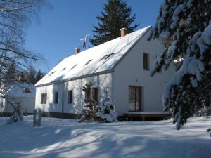 une maison blanche avec de la neige au sol dans l'établissement Penzion Blanko, à Nová Bystřice