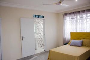een slaapkamer met een bed met een geel hoofdeinde en een raam bij KOJOSVILLA LUXURY APARTMENT in Tema
