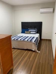 um quarto com uma cama e piso em madeira em Apartamentos IVAGO em Encarnación