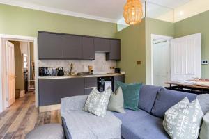 a living room with a blue couch and a kitchen at Stunning Boutique Flat in Central Location - Alfred in Bath