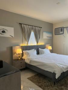 a bedroom with a large bed with white sheets and pillows at شقق ثمانين بارك1 in Khamis Mushayt