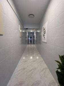 an empty hallway with white tile walls and a long hallway at شقق ثمانين بارك1 in Khamis Mushayt